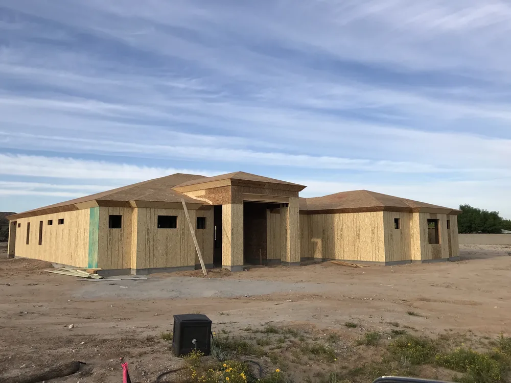 Broad single-story custom home with sheathing and roof framing in place